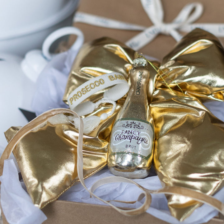 LNH Edit Golden Luxe Gift Box with champagne ornament and gold bow decoration.