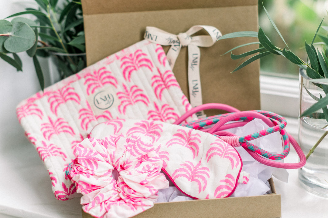 Close-up of LNH Edit Pink Palm Gift Set including pouch, scrunchie, eye mask, and pink phone cord.