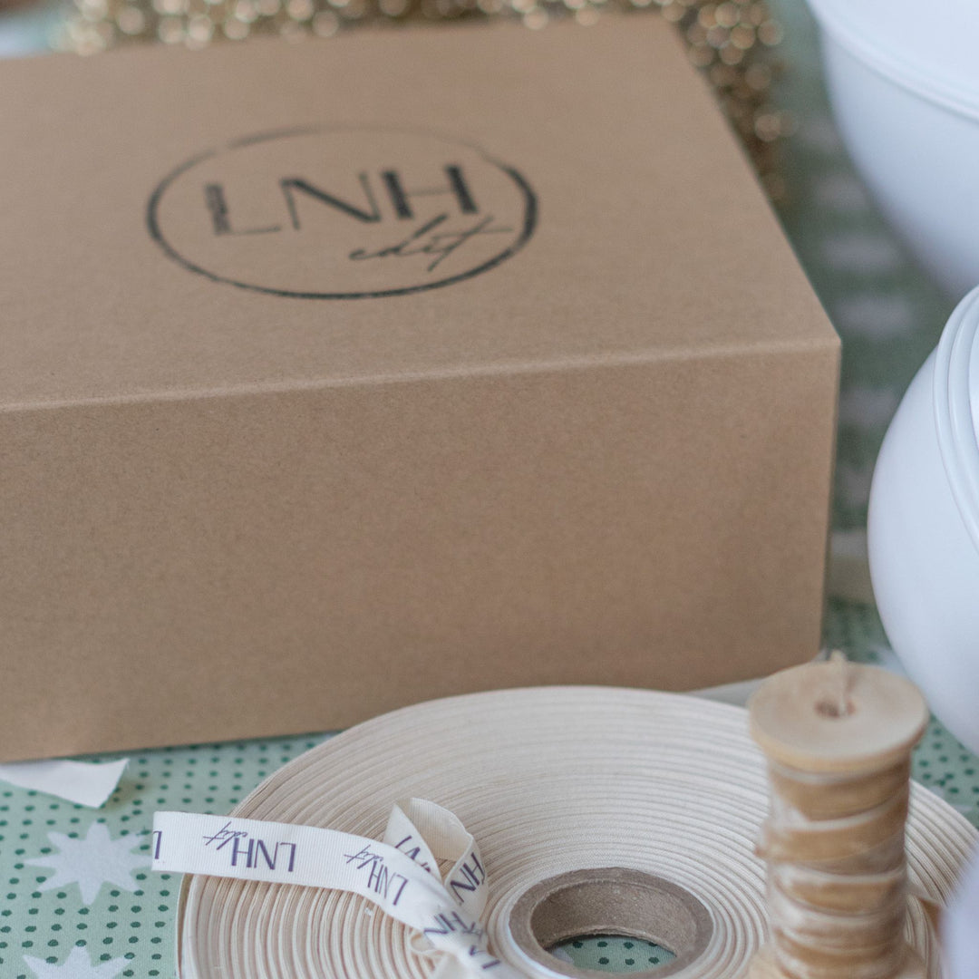 LNH Edit kraft gift box with branded ribbon roll and festive decor.