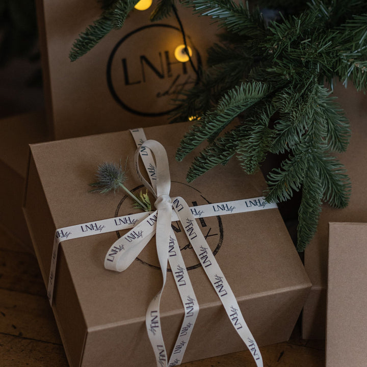 LNH Edit kraft gift boxes tied with branded ribbon under Christmas tree.