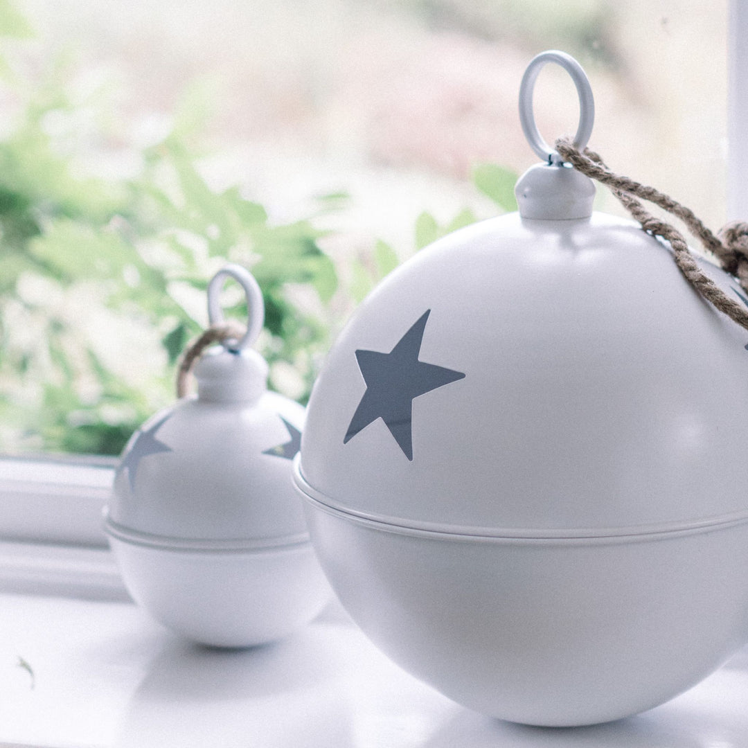 LNH Edit white star baubles in two sizes styled on a bright window ledge with fresh greenery.