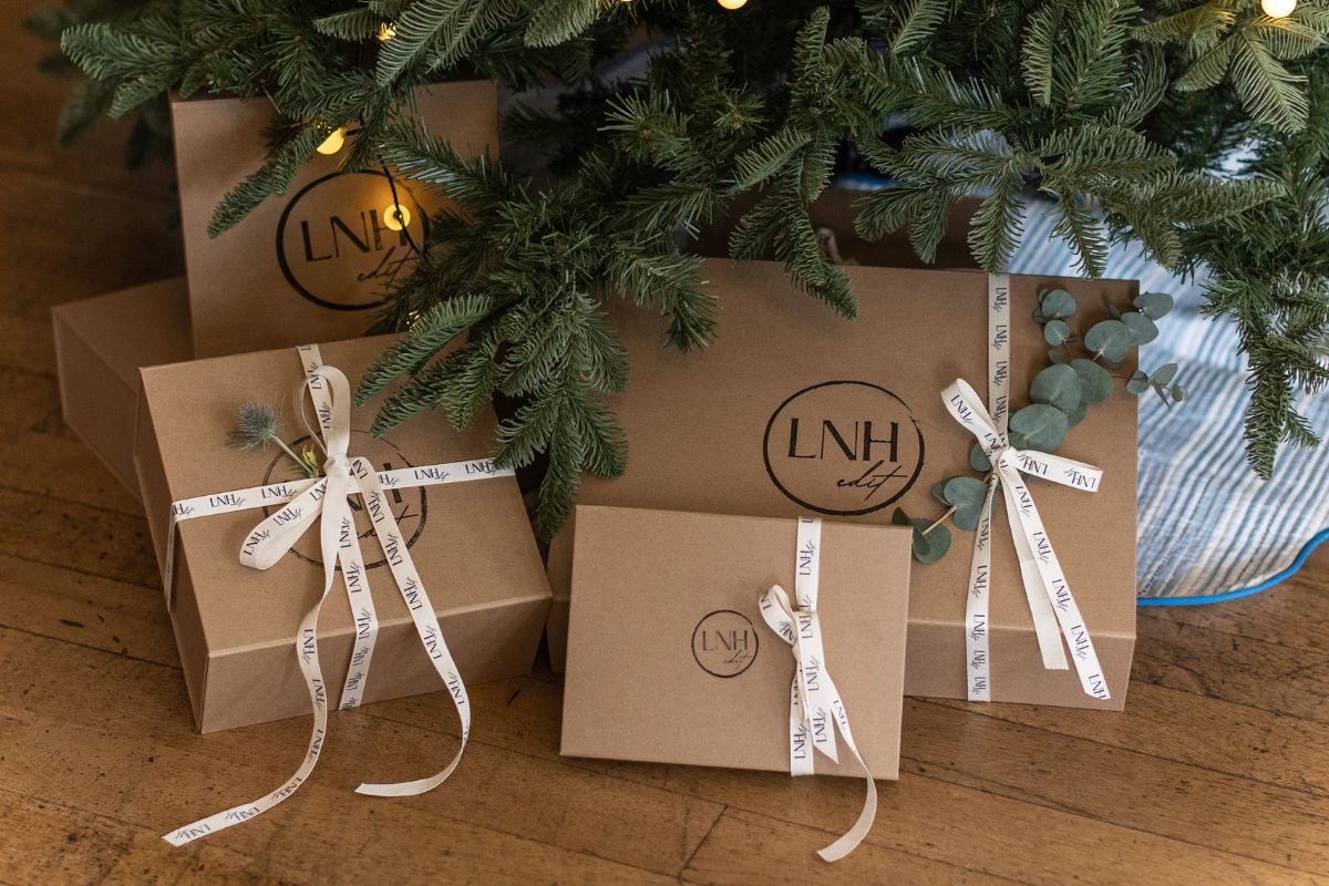 LNH Edit kraft gift boxes tied with branded ribbon displayed under a Christmas tree.