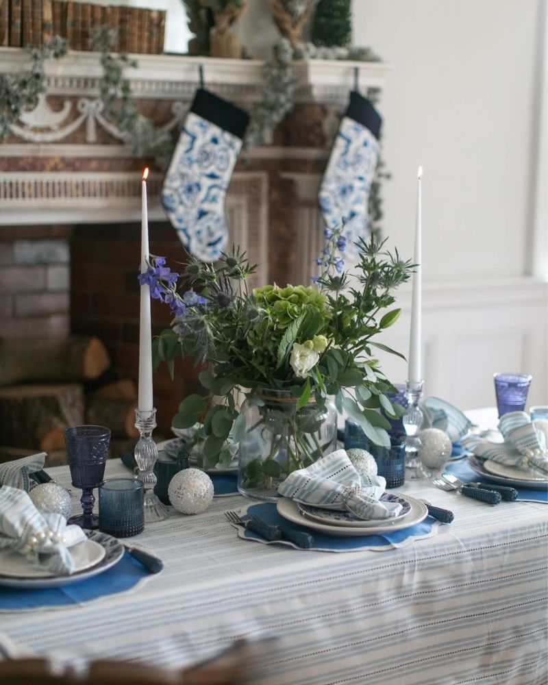 Elegant Christmas hosting tablescape with blue glassware, striped linens, candles, and festive greenery – LNH Edit