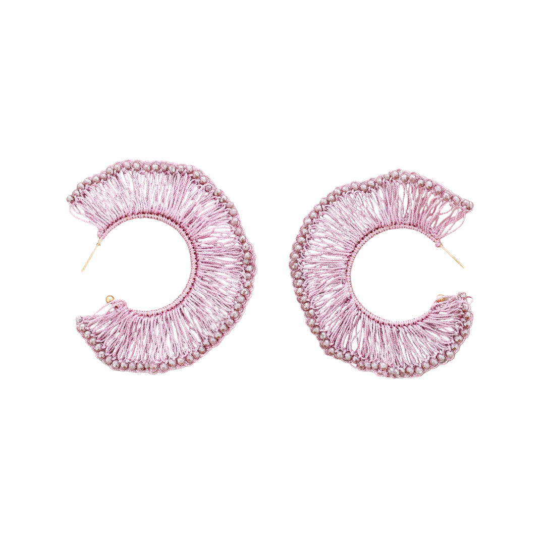 Pair of pink embroidered hoop earrings on a beige background