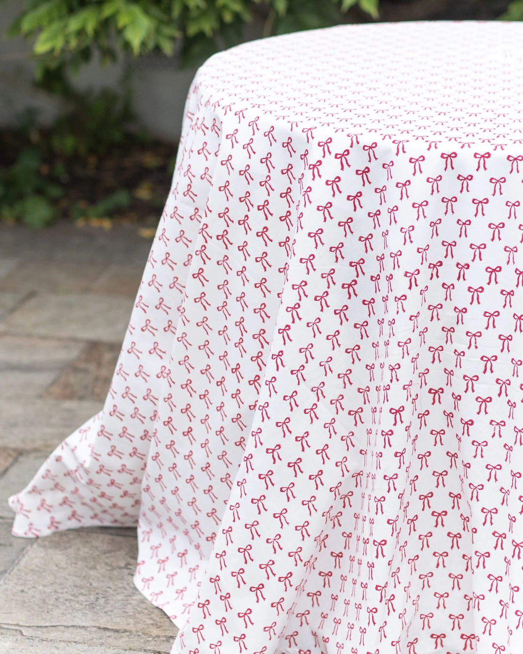 Hand block-printed red bow cotton tablecloth detail, soft drape and festive pattern.