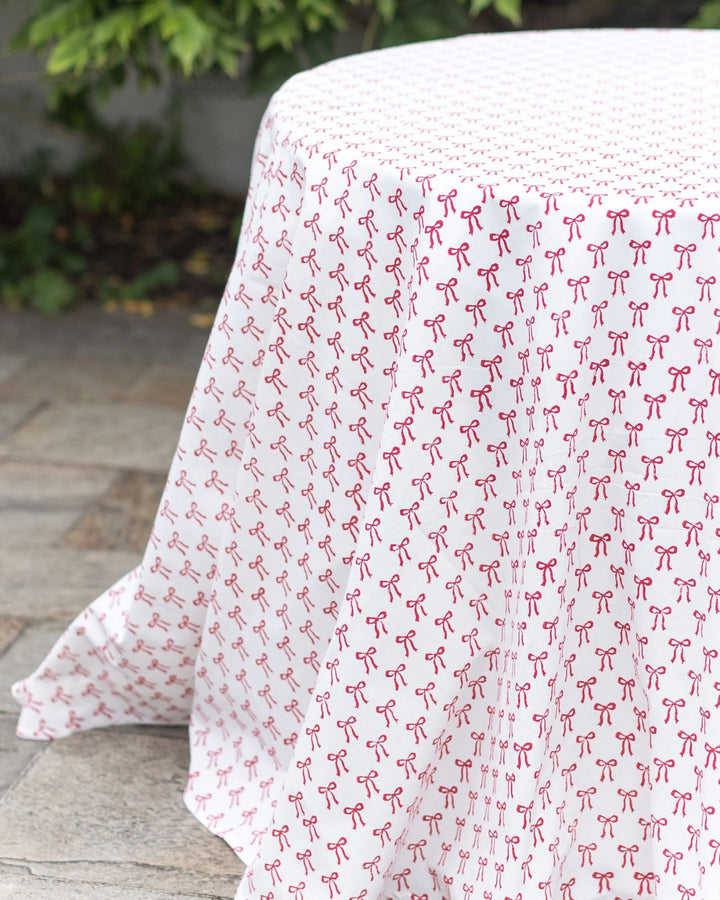 Hand block-printed red bow cotton tablecloth detail, soft drape and festive pattern.