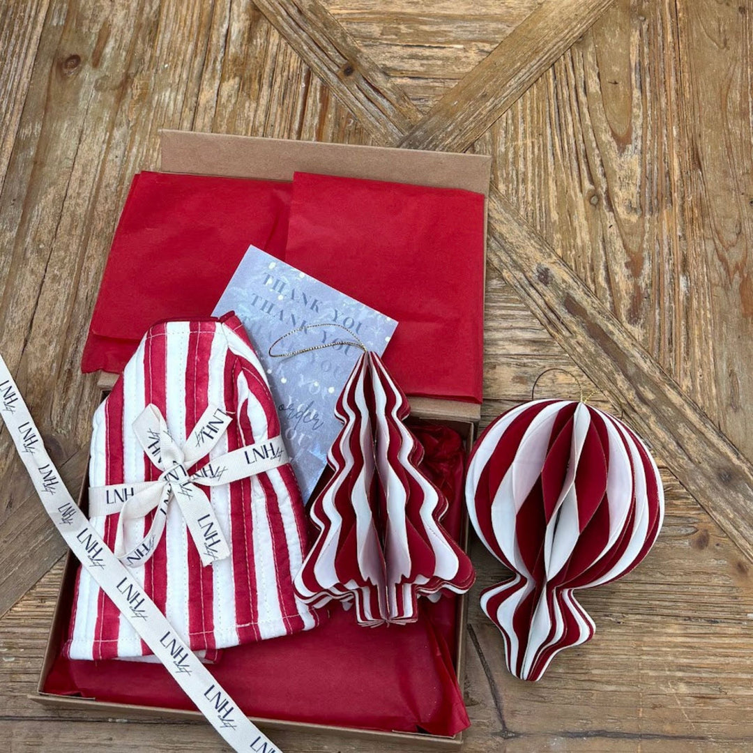 LNH Edit Christmas Red Stripe Gift Box with red striped tissue cover, paper decorations, and LNH ribbon packaging on wooden table.
