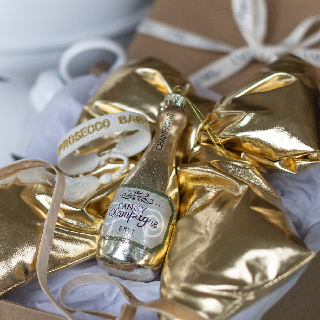 Golden Luxe Christmas gift box with festive champagne decorations and gold ribbon.
