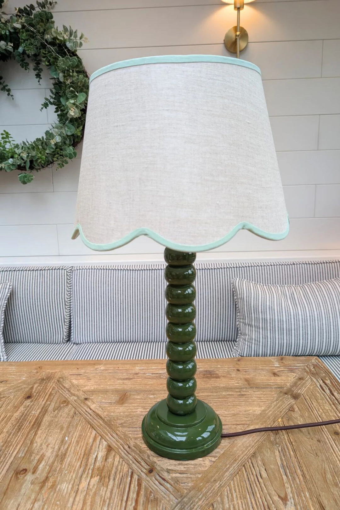 Hand-painted green bobbin tall lamp base with glossy finish on wooden table.