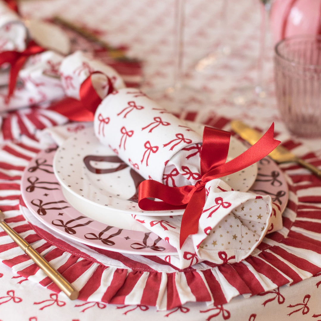 Close-up of red and white Christmas cracker with bow print on festive table from The Holly Collection by LNH Edit.