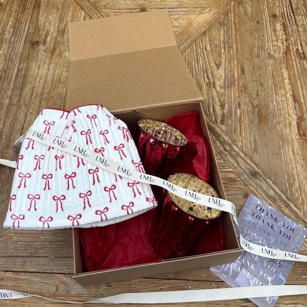 Housewarming gift box with red bow-printed cotton tissue box cover and two large red tealight holders in kraft packaging.