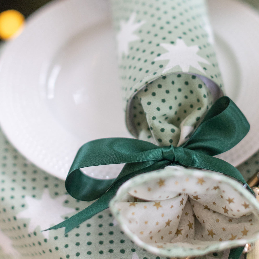Closeup of Mistletoe Green reusable Christmas crackers with ribbon and star print fabric.