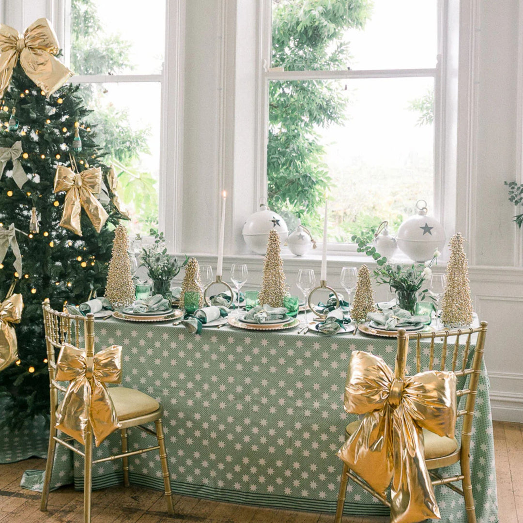 LNH Edit Mistletoe green star block-printed cotton tablecloth styled with Christmas tree and greenery in bright festive dining room.