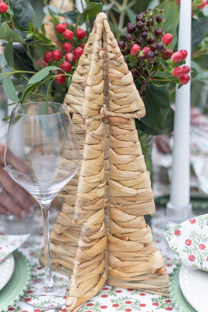 Handwoven wicker Christmas tree on a festive table with floral arrangement and glassware