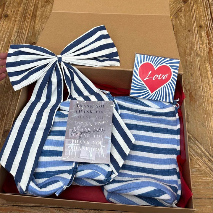 Stripey Love Gift Box featuring striped cosmetic bags, blue oversized bow and Love matchbox arranged in a kraft gift box.