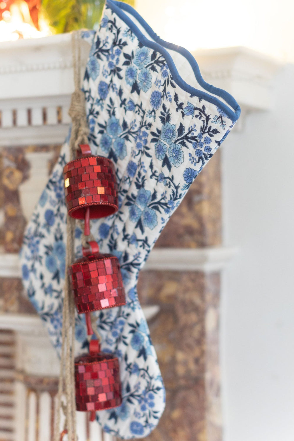 LNH Edit Thistle Blue Quilted Christmas Stocking in hand block-printed cotton with blue floral pattern, hanging by a fireplace.