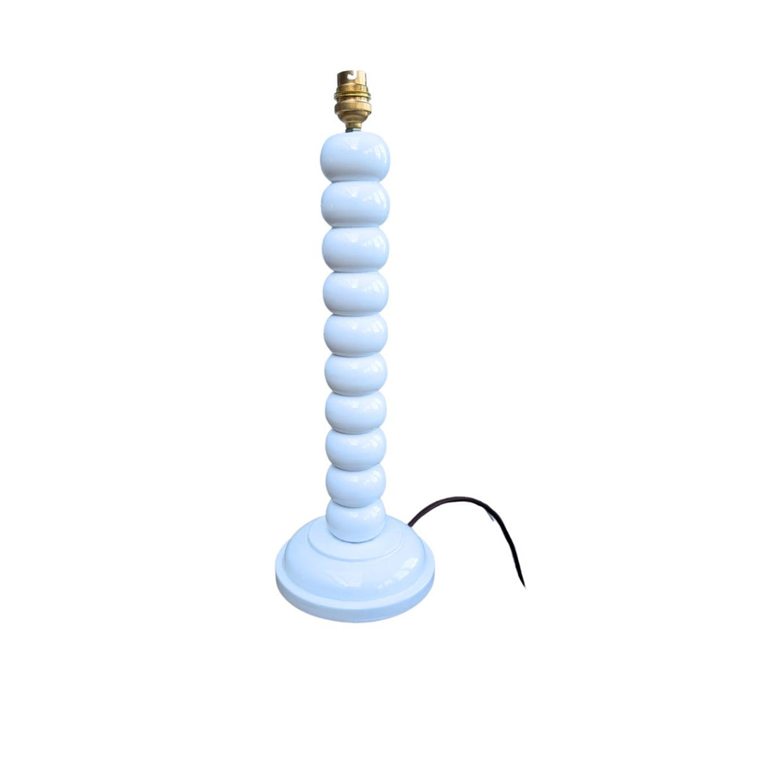 White hand-painted bobbin lamp base with gold bulb fitting on a white background.