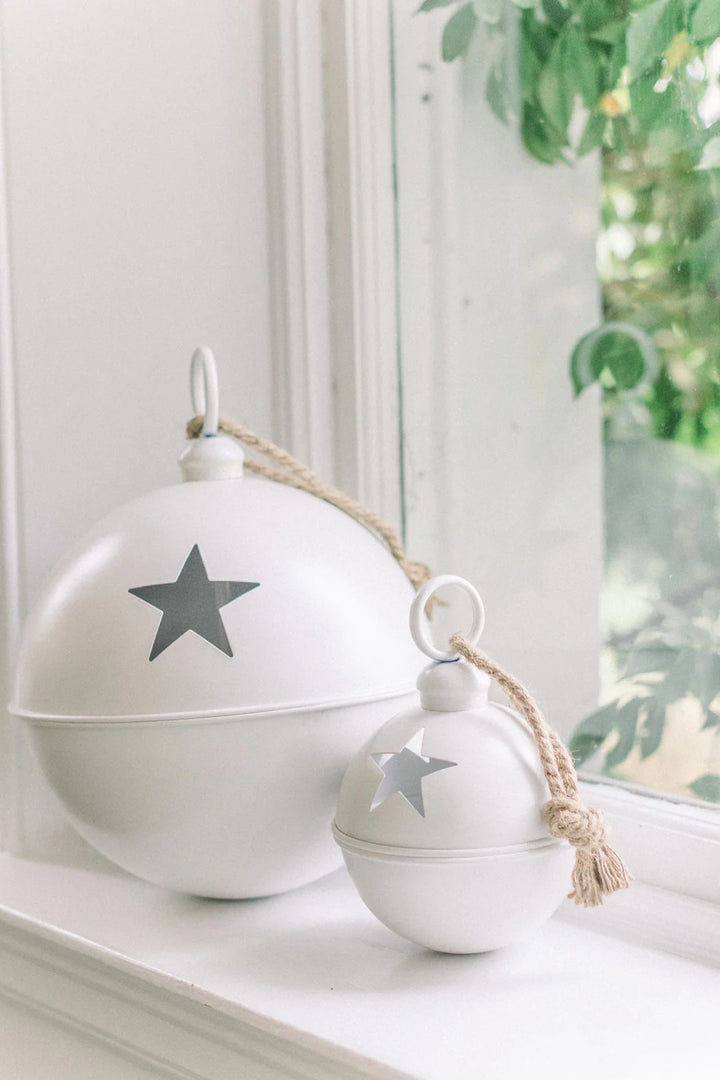 LNH Edit white metal star baubles with jute rope handles displayed on a bright windowsill in a festive home setting.
