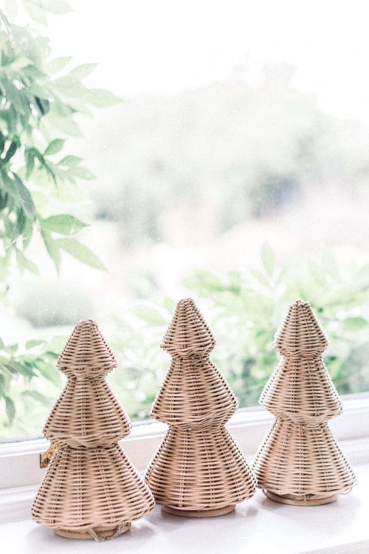 LNH Edit wicker Christmas trees on a windowsill with soft greenery in the background.