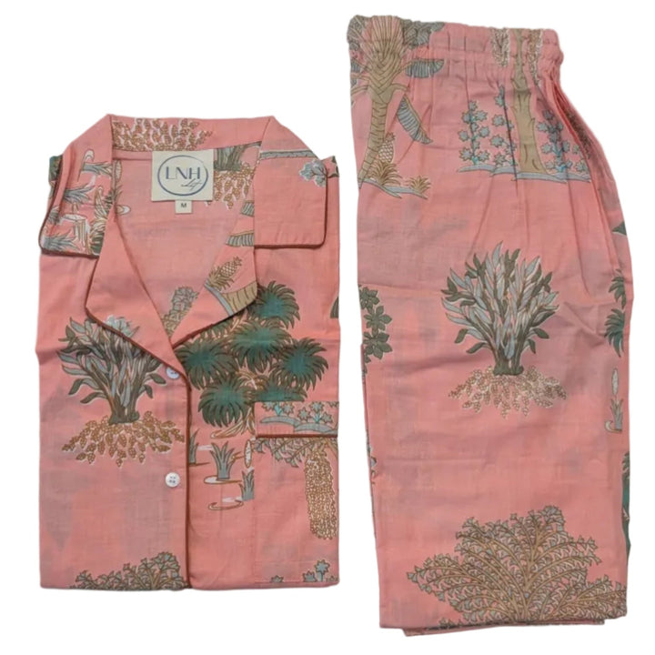 Peach-colored pajama set with green floral patterns on a light gray surface.