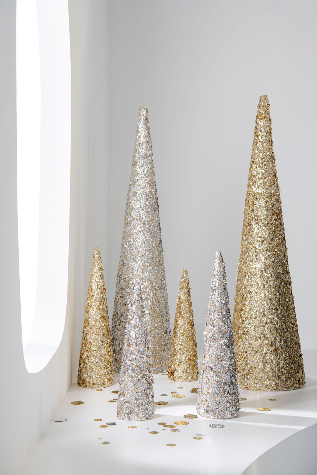 Champagne and silver sequin cone trees styled together in a modern festive display.