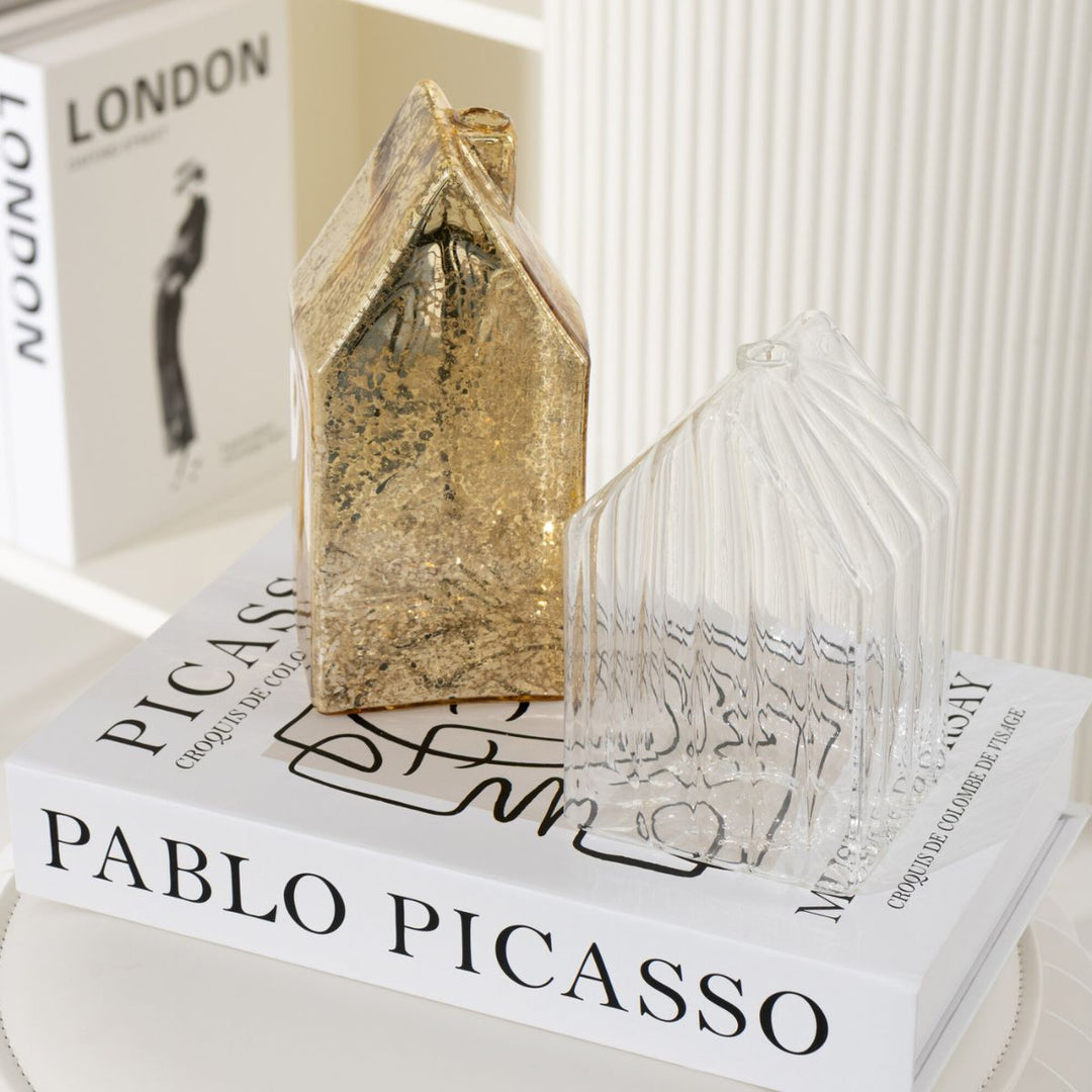 Pair of gold glass houses styled on a coffee table book, elegant festive home décor.