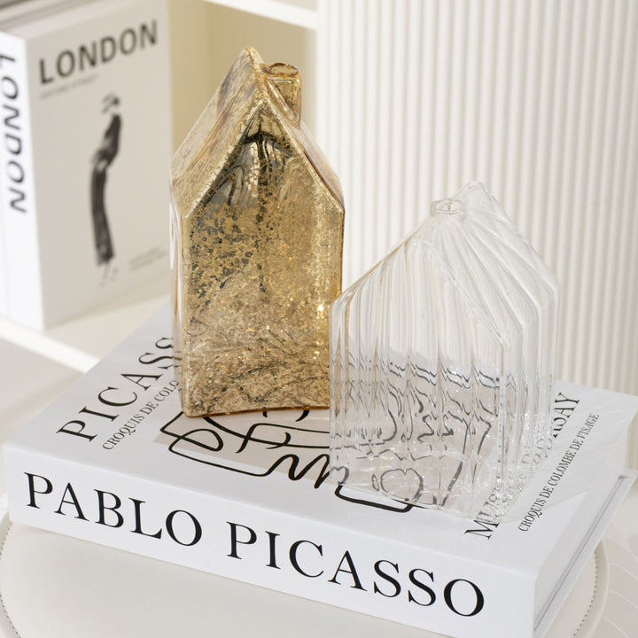 Pair of gold glass houses styled on a coffee table book, elegant festive home décor.