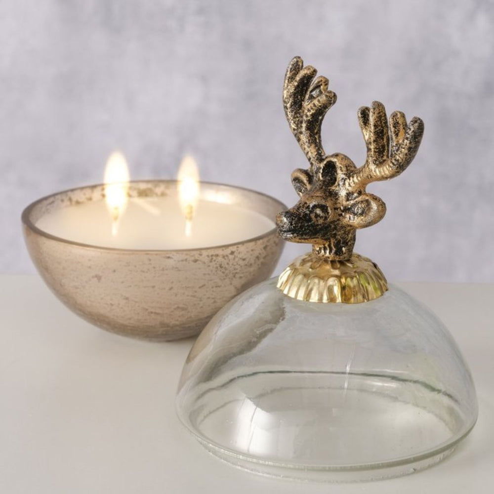 Gold candle pot with reindeer lid beside lit candle, elegant Christmas styling.