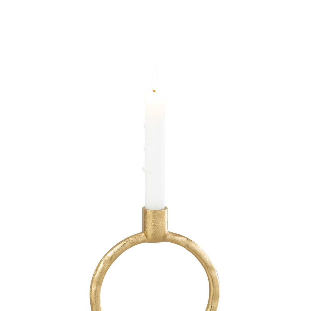 Gold ring candleholder with white taper candle lit.