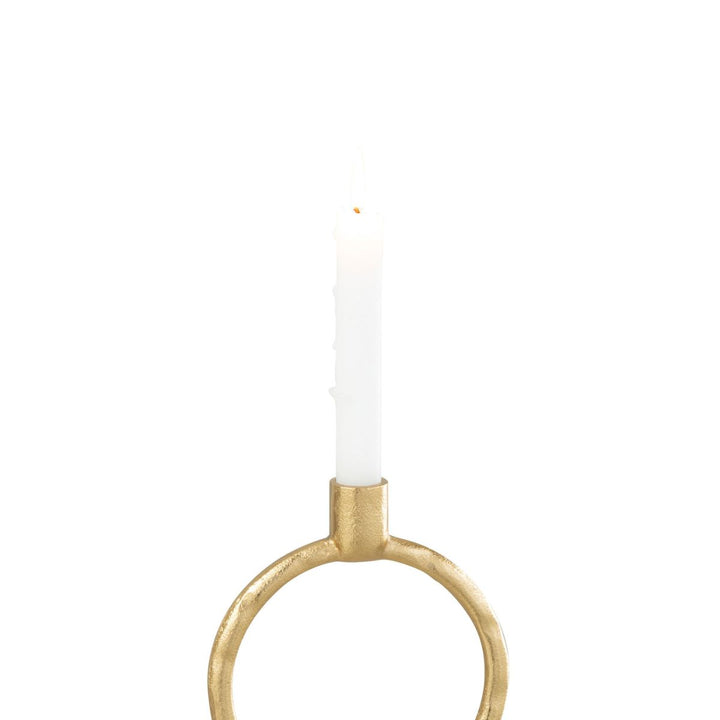 Gold ring candleholder with white taper candle lit.