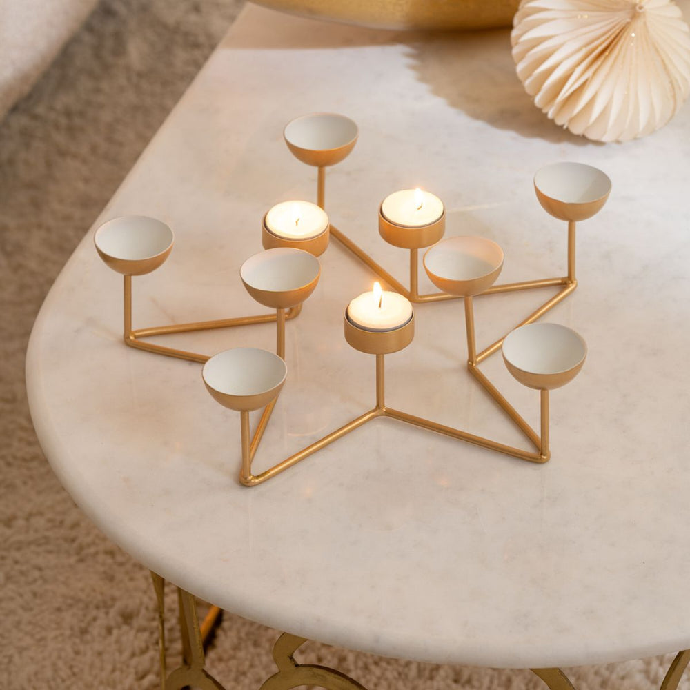 Gold star tealight holder styled on a marble table with festive décor.