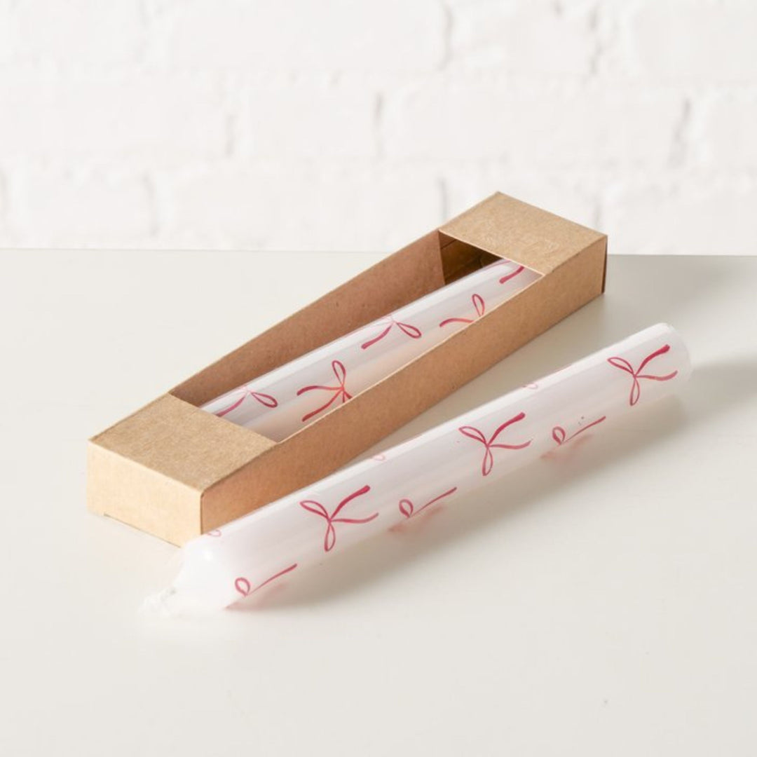 Two festive bow motif taper candles styled with natural Kraft box.