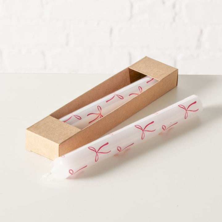 Two festive bow motif taper candles styled with natural Kraft box.