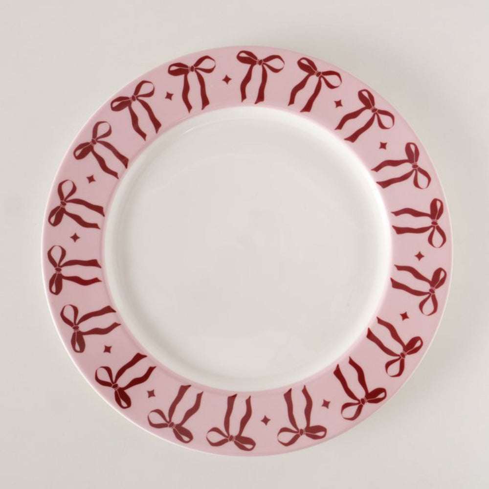 Overhead view of light pink ceramic plate with red bow border.