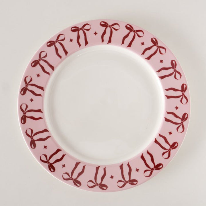 Overhead view of light pink ceramic plate with red bow border.