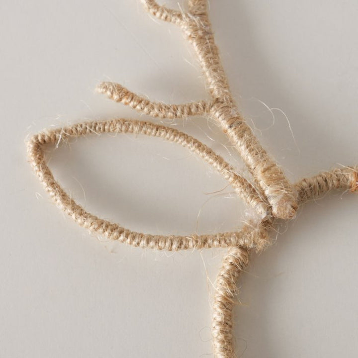 Close-up of handcrafted jute reindeer antler napkin ring showing natural woven texture.