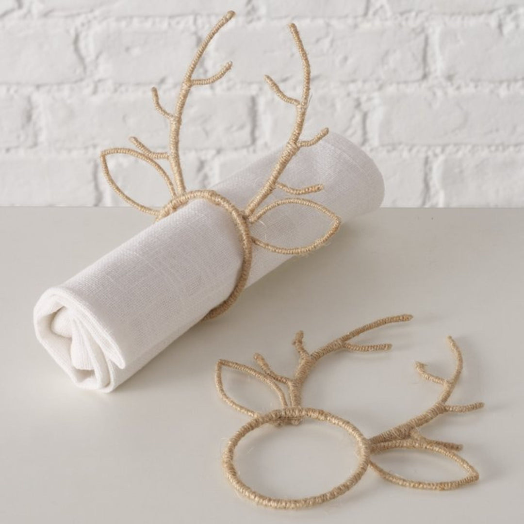 Reindeer antler napkin ring displayed on a rolled white linen napkin for festive table styling.