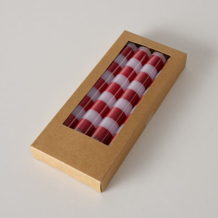 Close-up of boxed red and white striped candles with clear window packaging.