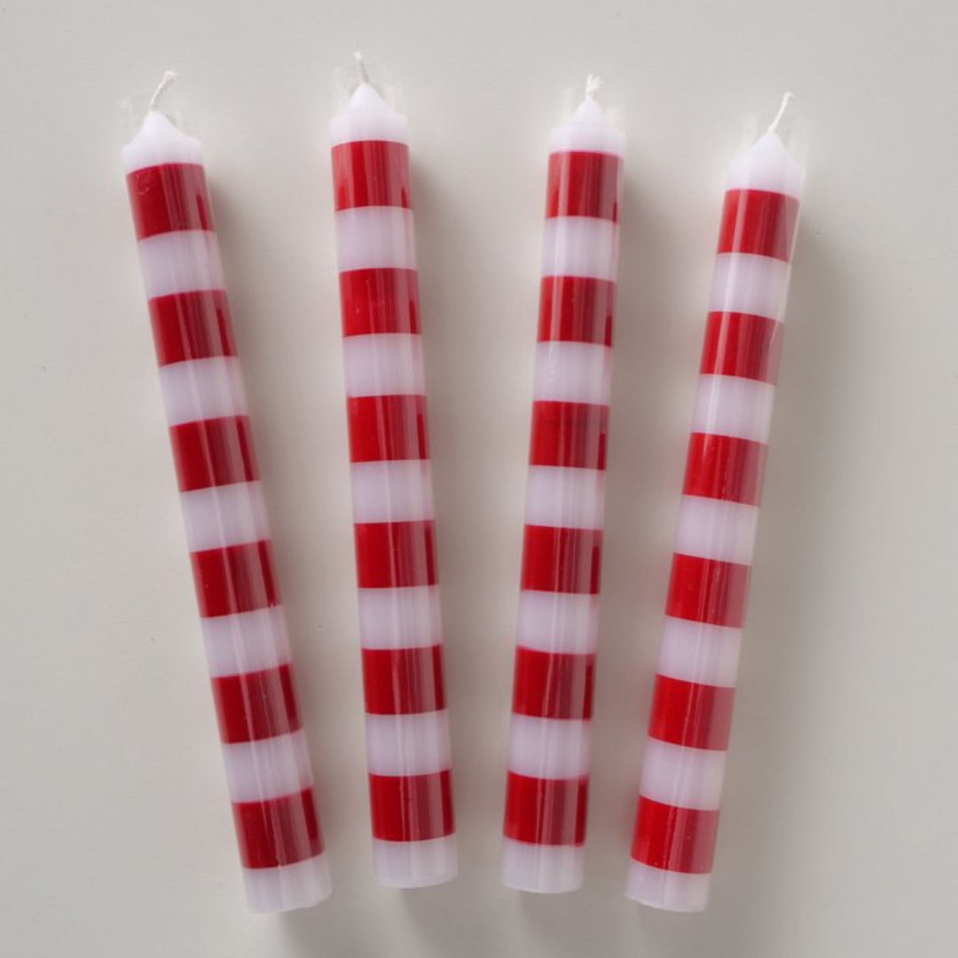 Flat lay of four festive red and white striped taper candles.