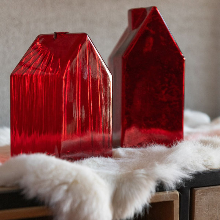 Pair of red glass houses styled on soft faux fur surface, festive home décor.