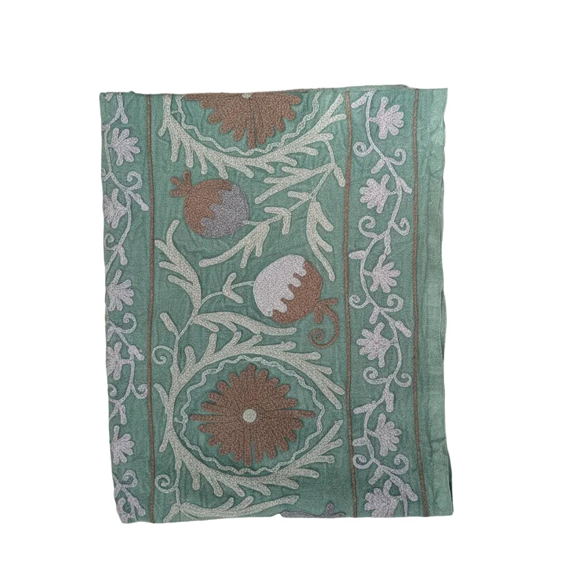 A folded piece of mint green fabric with traditional floral and vine embroidery in brown, beige, and white, shown against a plain white background.