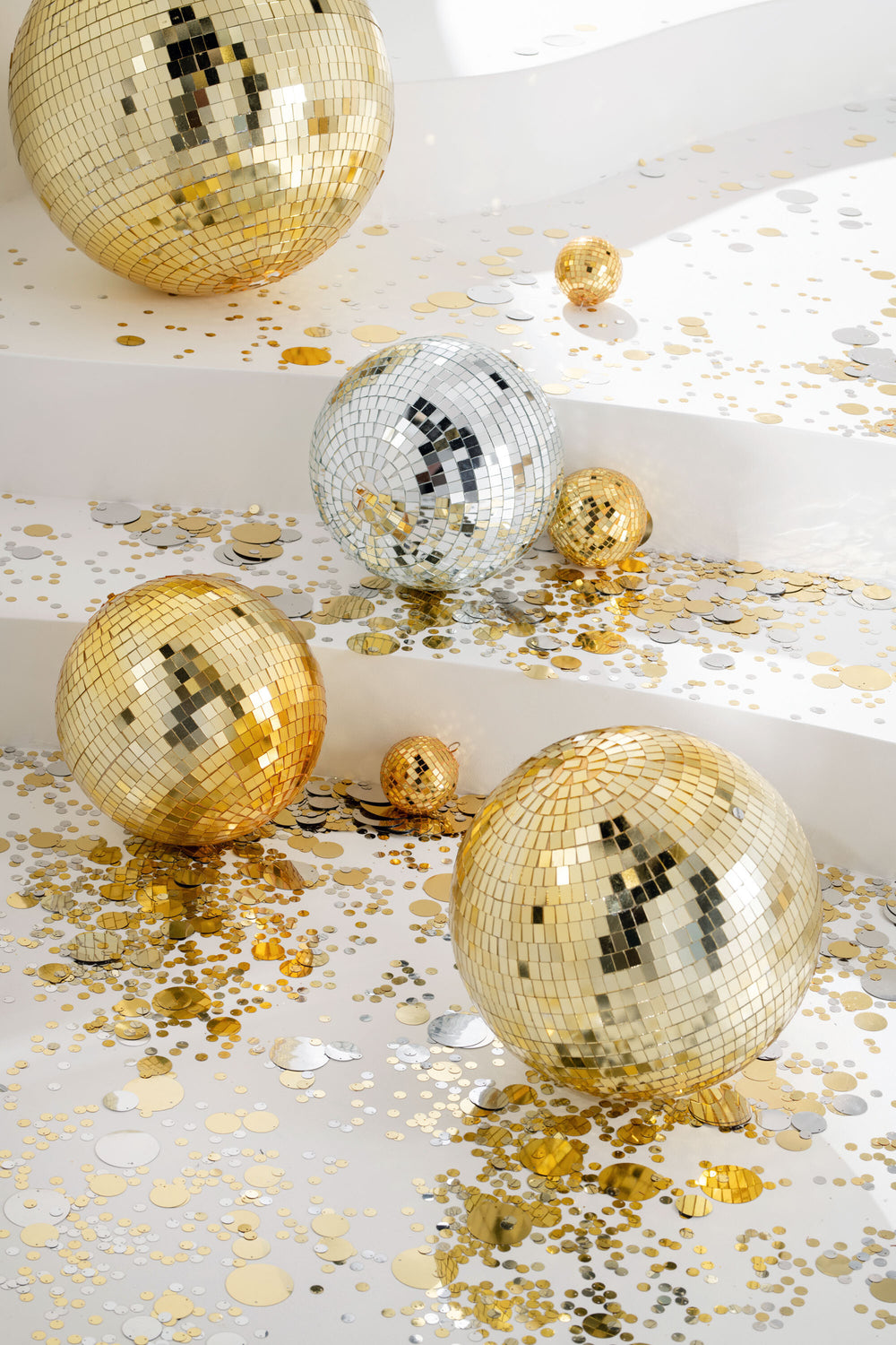 Gold and silver disco balls styled together with gold confetti for festive décor.