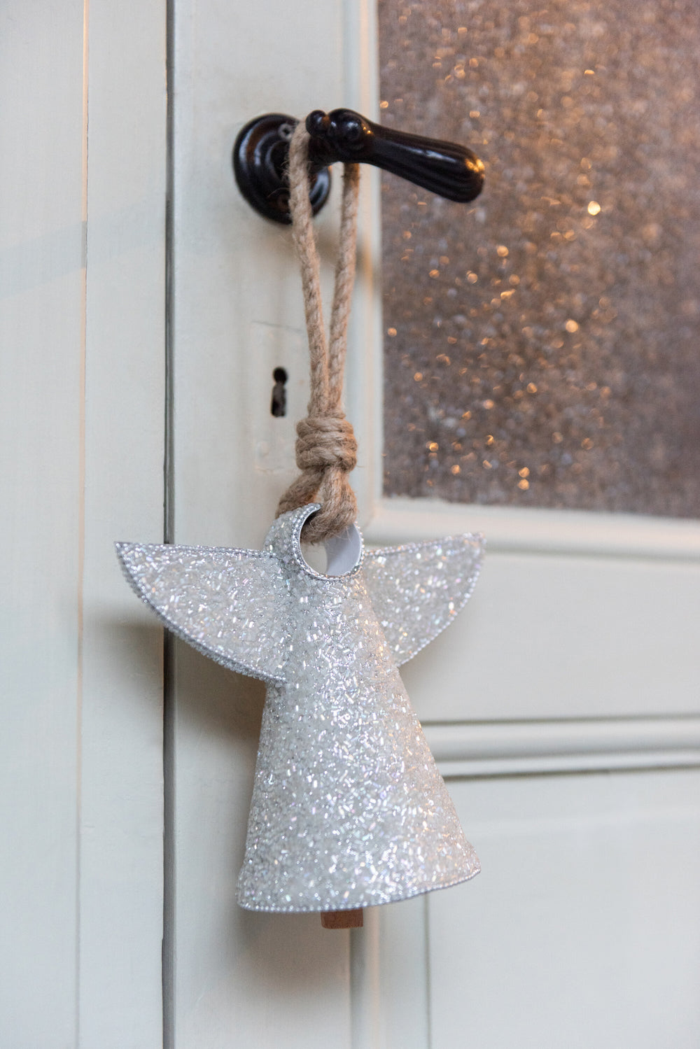 Silver glitter angel bell hanging as part of festive Christmas décor.