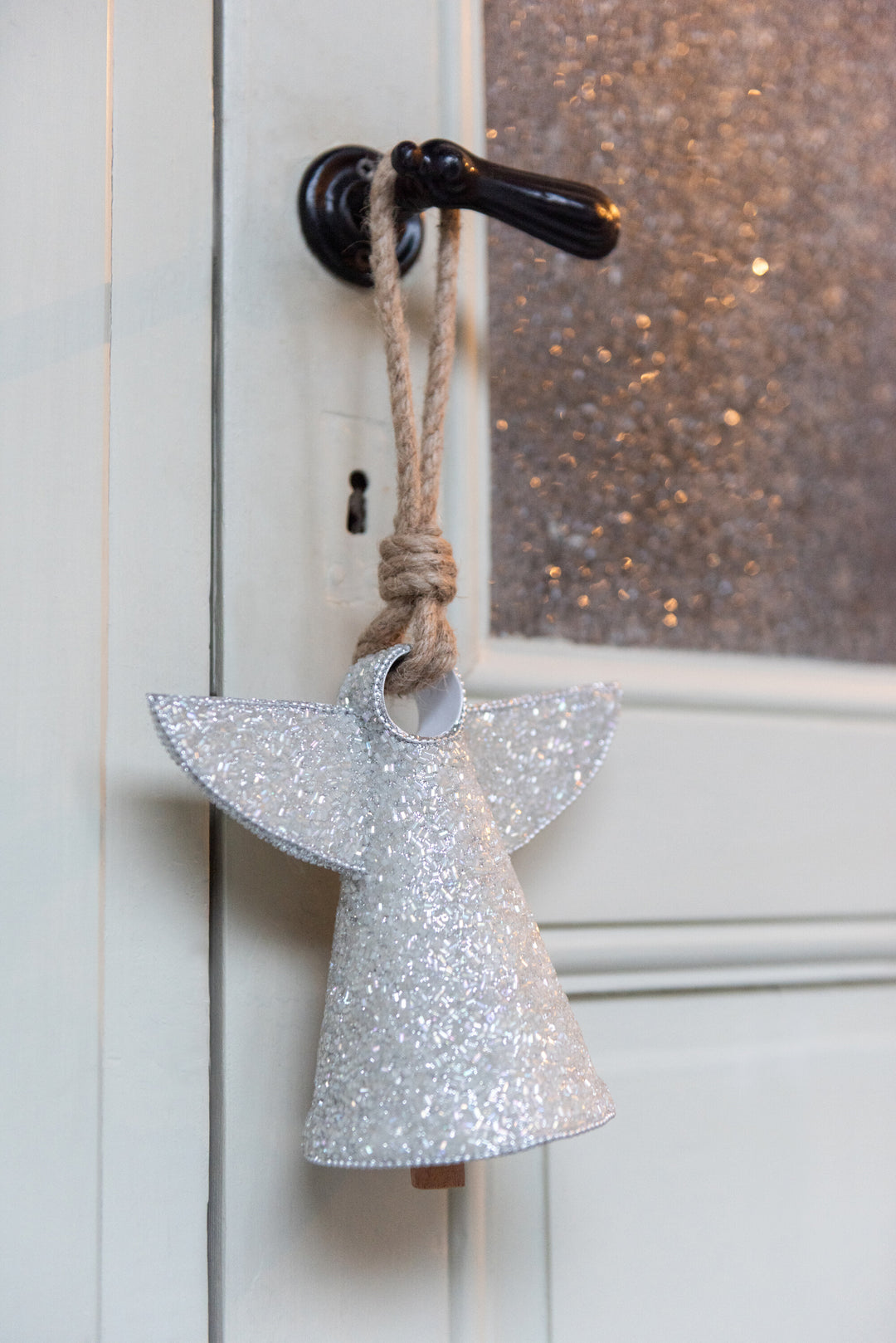 Silver glitter angel bell hanging as part of festive Christmas décor.