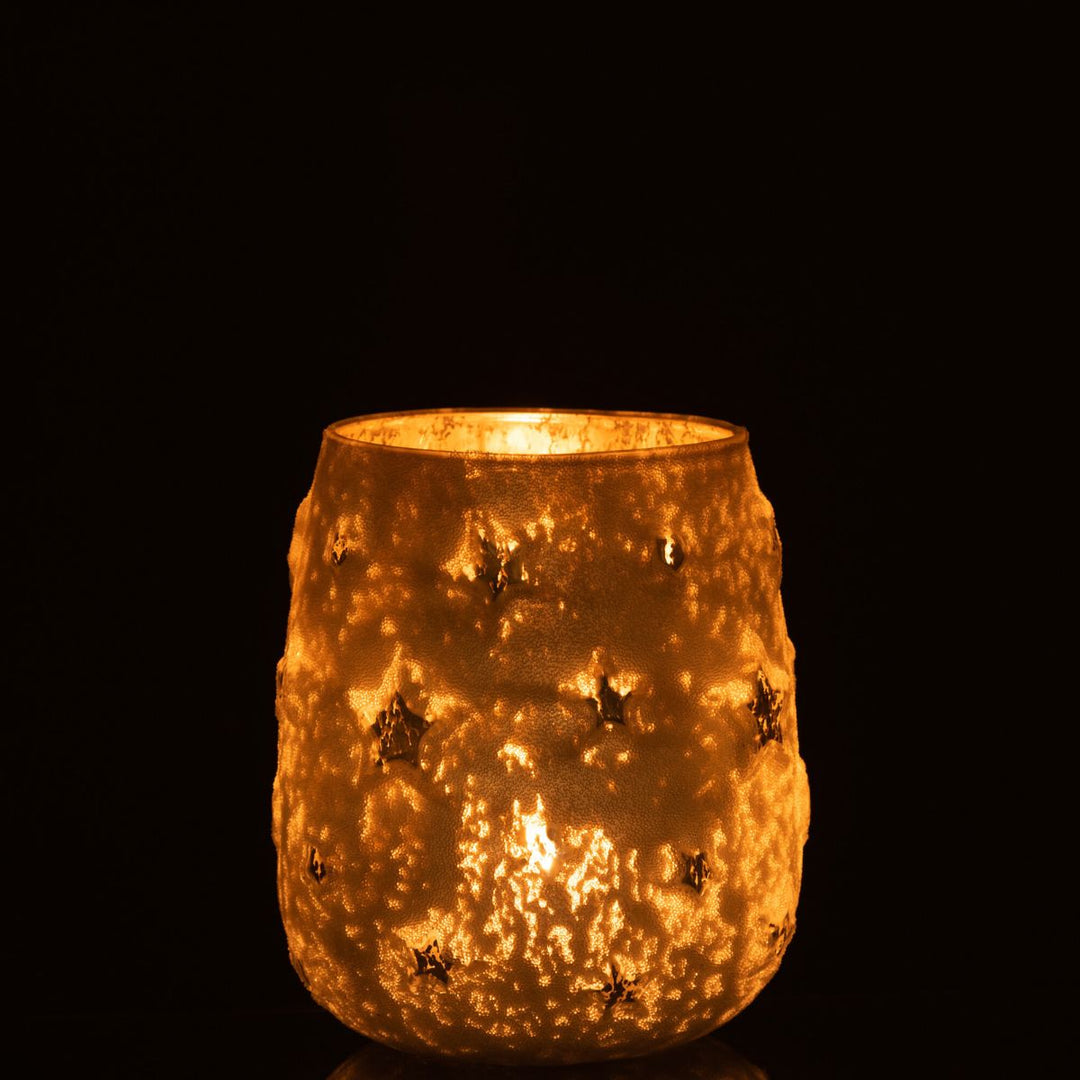 Star cut-out glass tealight holder glowing warmly in the dark.