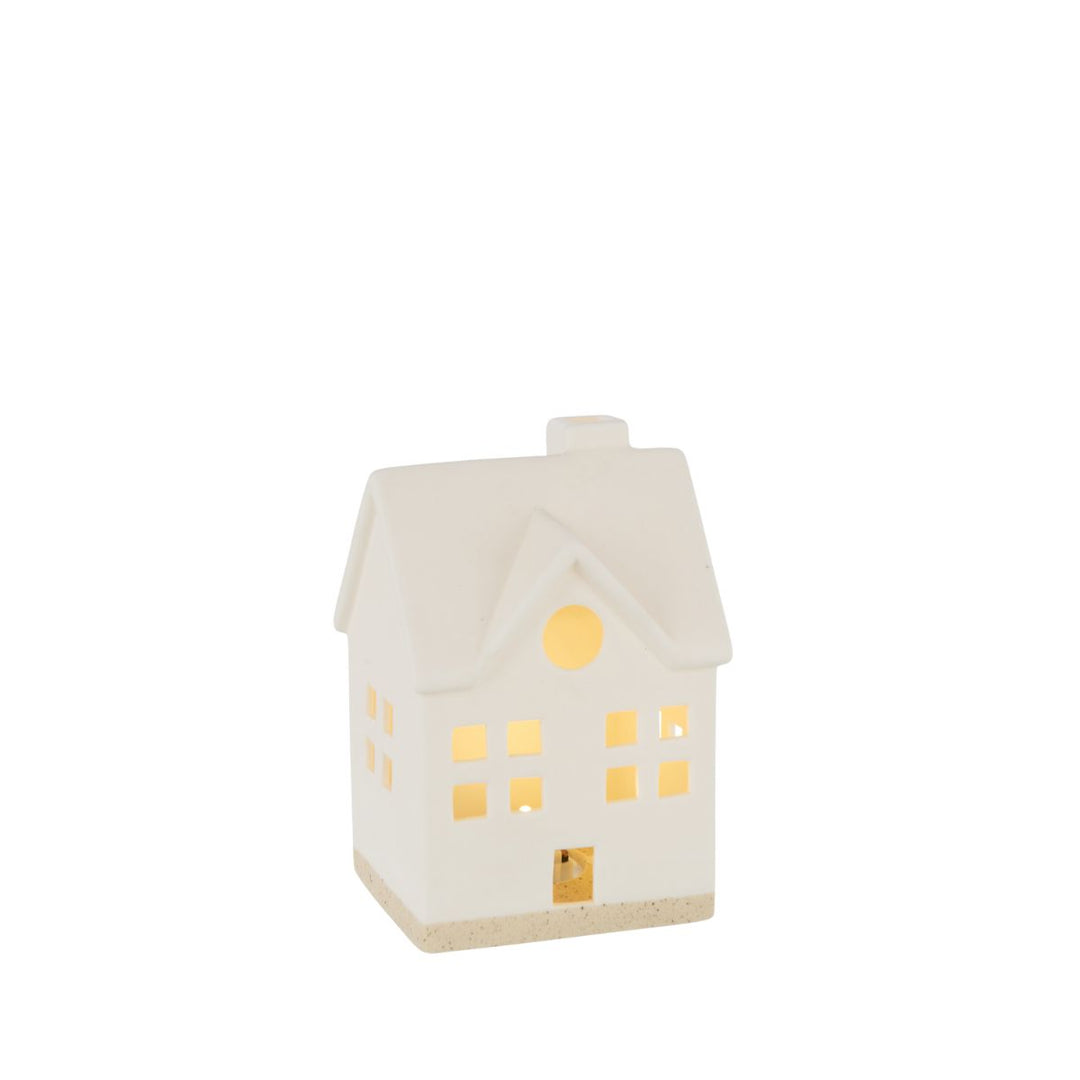 White ceramic LED house glowing warmly, soft Christmas lighting.