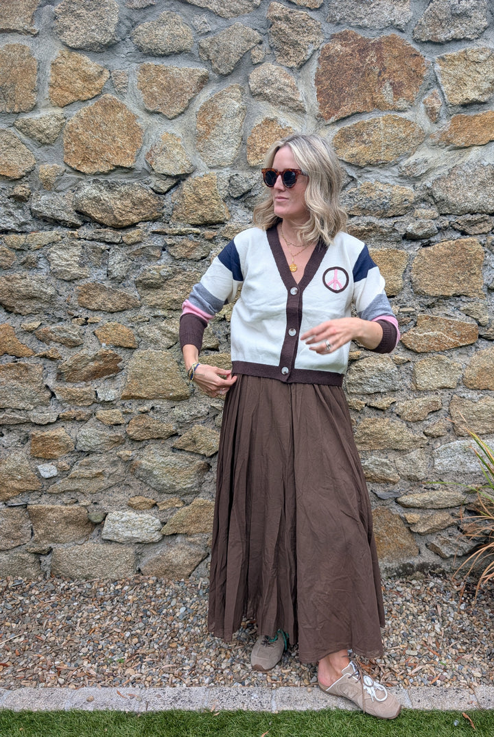Front view of multicolored peace cardigan, V-neck knit with relaxed fit, styled with maxi skirt.